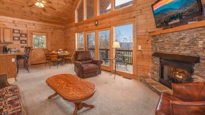 A spacious wooden cabin interior with a dining area, a fireplace, and a television mounted on the wall. - Gorgeous View Cabin  Hot Tub  Privacy  Fireplace  Pool   Fishing Access (Sevierville)