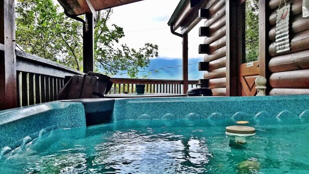 A hot tub with a view of the mountains, wooden deck, and a covered seating area. - Gorgeous View Cabin  Hot Tub  Privacy  Fireplace  Pool   Fishing Access (Sevierville)
