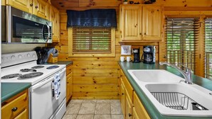 Une cuisine avec des armoires en bois, une cuisinière, un four à micro-ondes et un évier.