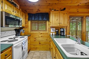 Une cuisine avec des armoires en bois, une cuisinière, un four à micro-ondes et un évier.