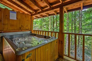 Eine Holzhütte mit Whirlpool und Blick auf den Wald.