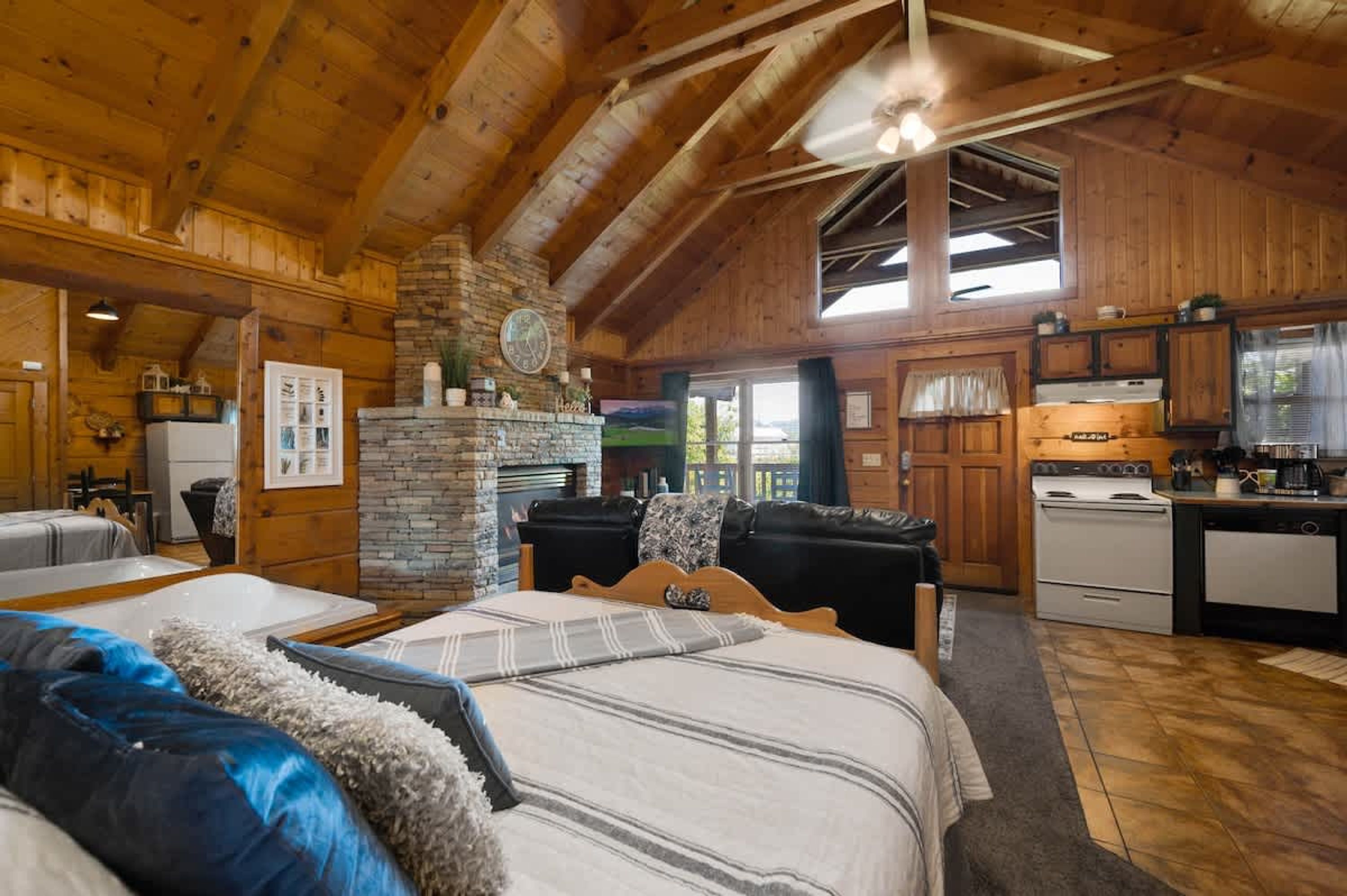Interior de una cabaña de troncos con una cama grande, una chimenea, una cocina y un comedor.