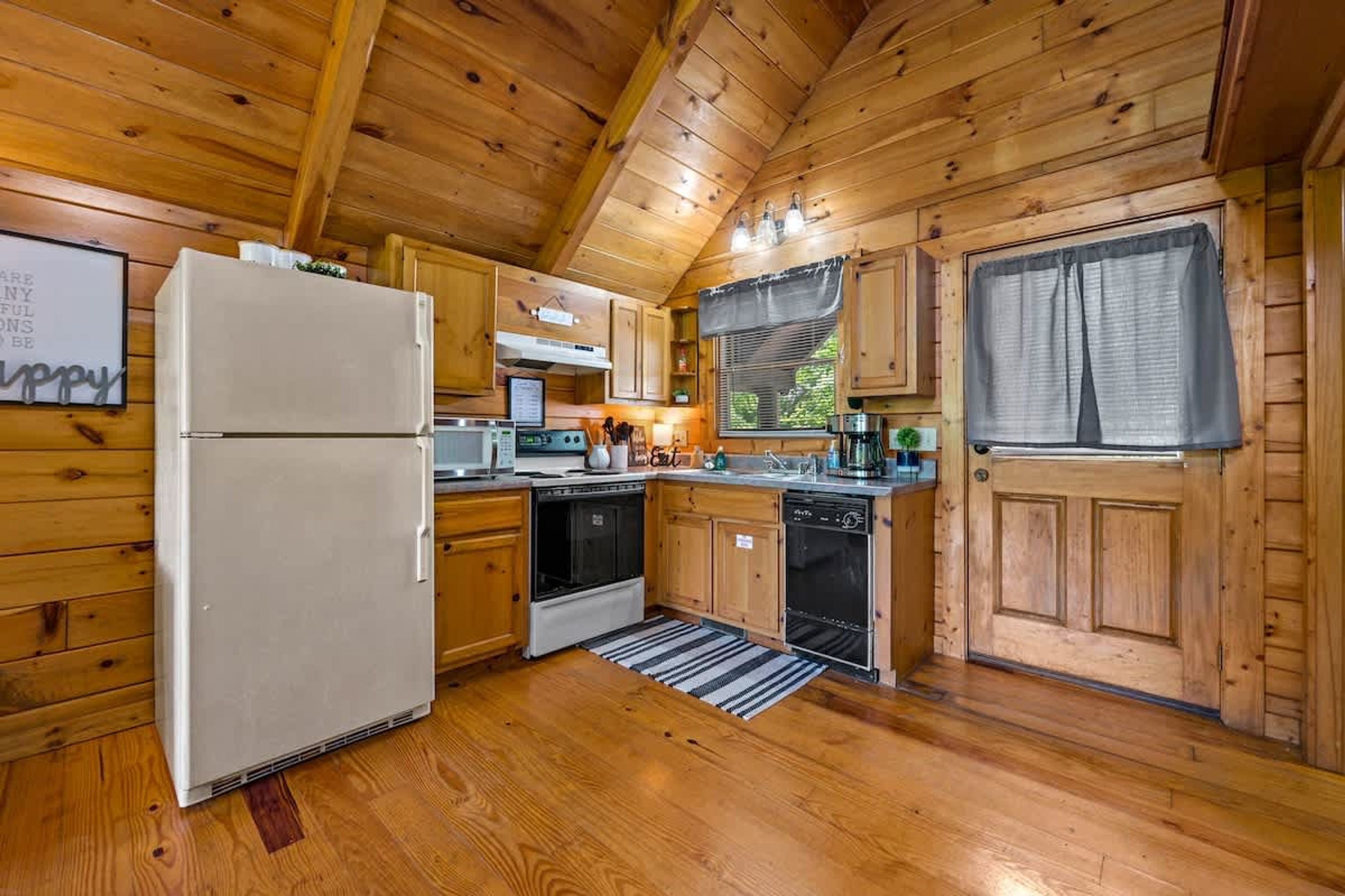 A wooden cabin kitchen with a refrigerator, oven, dishwasher, and wooden cabinets.