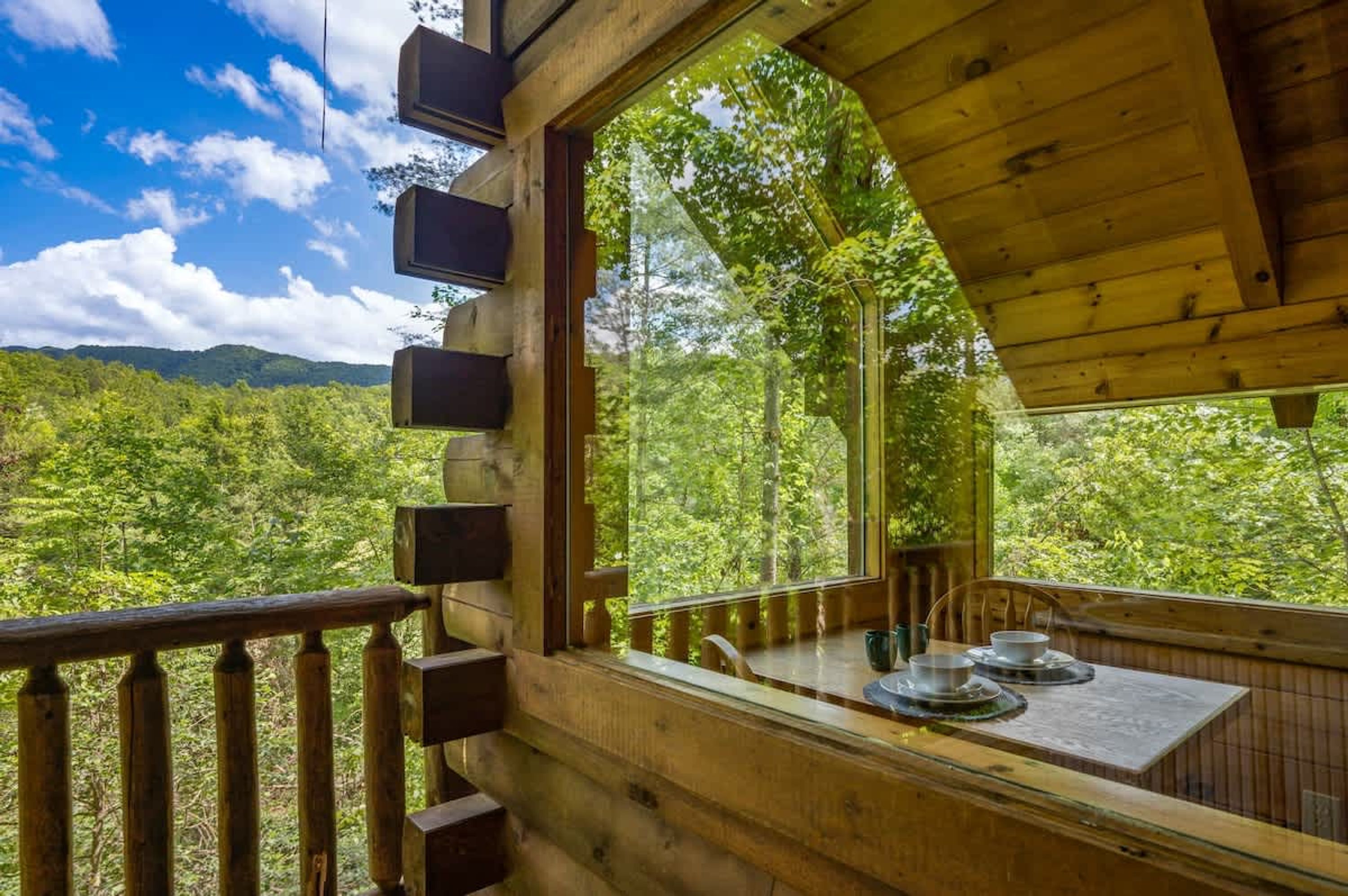 Une cabane en bois dotée d’une grande fenêtre donnant sur un paysage boisé.