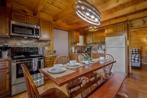 A wooden cabin-style kitchen with a central island, built-in microwave, stove, and refrigerator. - Nice View  Log Cabin Fireplace Hot Tub Pool Table (Sevierville)