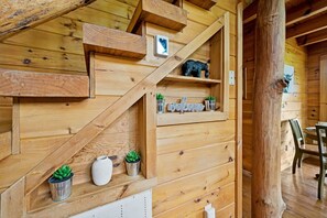 Un intérieur en bois avec un escalier, des étagères ornées d’objets décoratifs et un coin repas.
