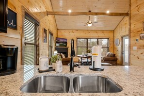 Una cocina con encimera de granito, pileta de acero inoxidable y electrodomésticos modernos.