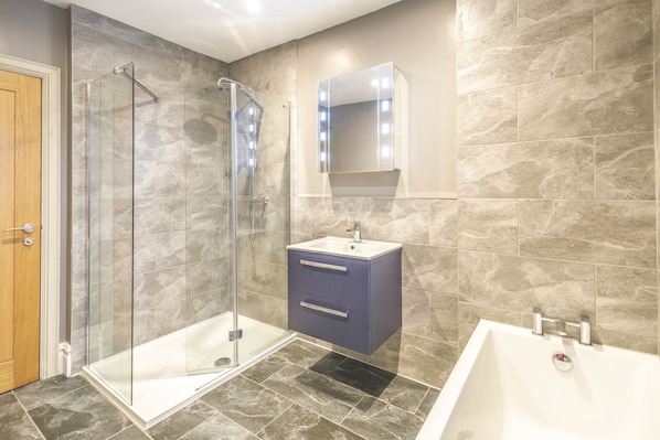 Une salle de bain moderne avec une douche à parois de verre, un meuble-lavabo avec un miroir et une baignoire.
