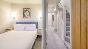 Une chambre d’hôtel comprenant un lit, une table de chevet, une œuvre d’art accrochée au mur et un escalier menant à un autre étage.