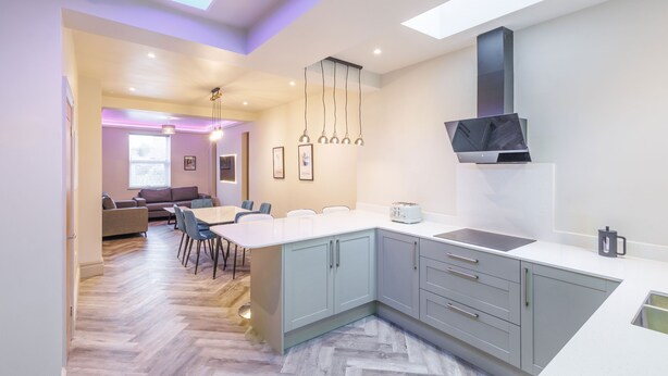 Une cuisine moderne dotée d’un grand îlot central, de meubles de couleur grise et de luminaires suspendus.