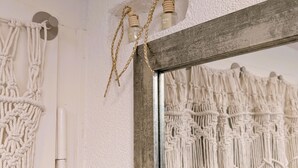 A room with a macrame wall hanging, a mirror with a wooden frame, and a macrame curtain.