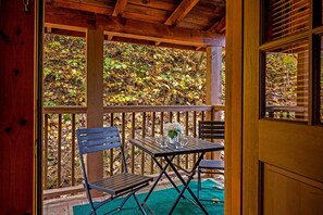 Terraza de madera con mesa y sillas, con vistas a un área boscosa.
