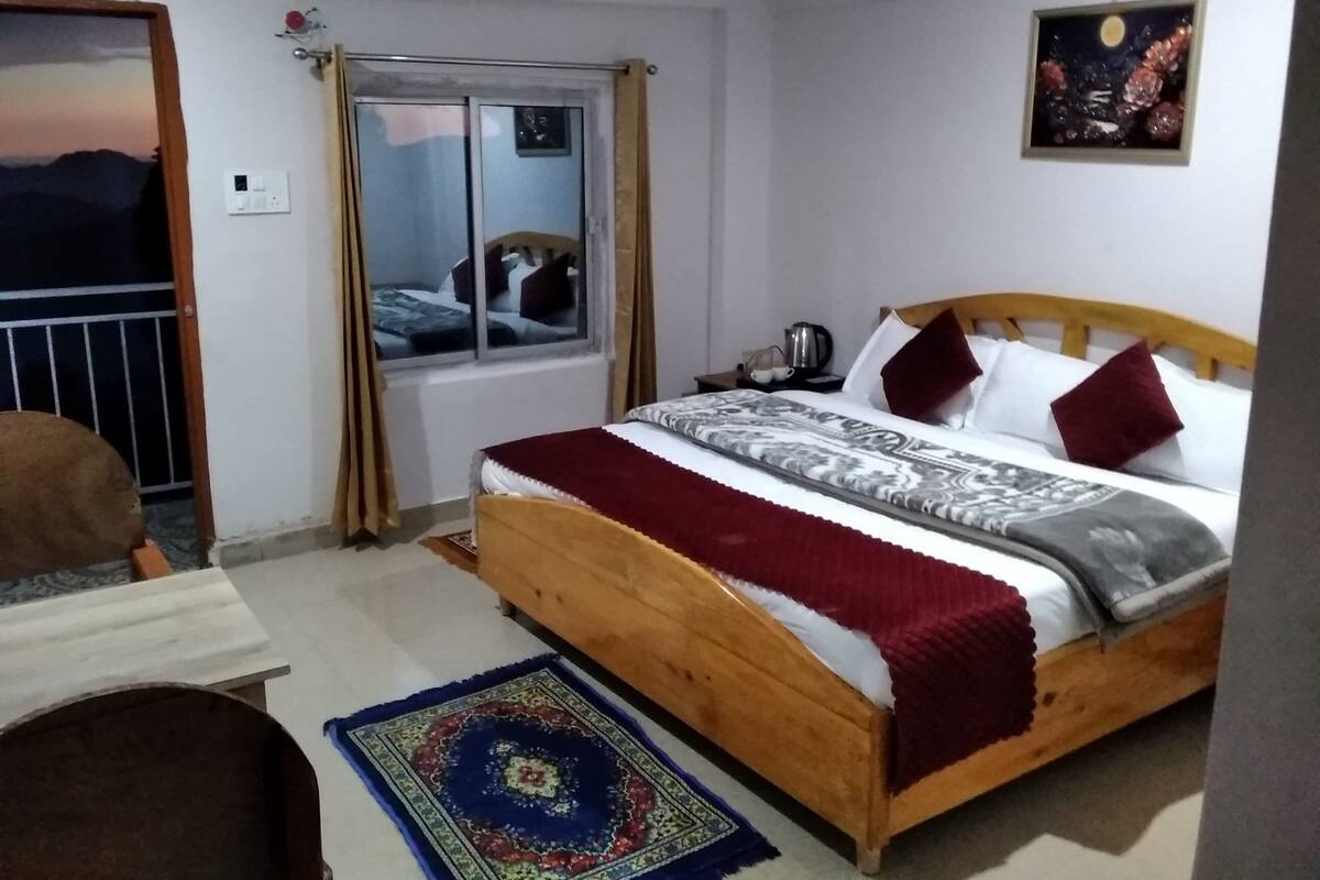 Un dormitorio con cama de madera, una ventana con cortinas, un cuadro de cielo nocturno y vistas al exterior.