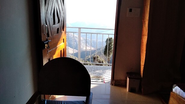 Quarto com cama, janela e vista de uma paisagem montanhosa.