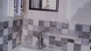 Um banheiro com pia branca, espelho e painel de azulejos.