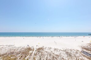 Ein Strand mit Holzsteg, Sand und blauem Himmel.