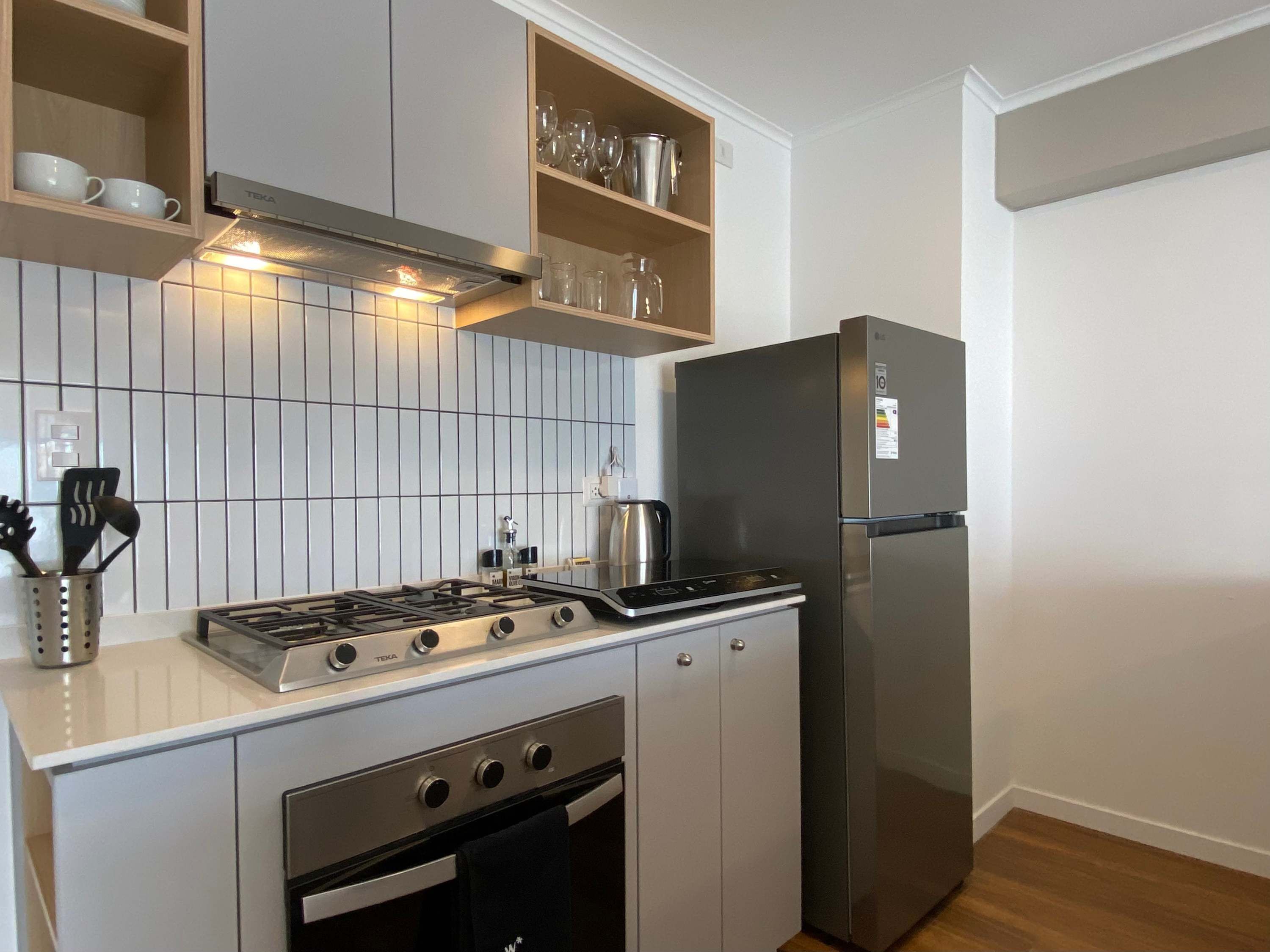 Cocina compacta con estufa a gas, horno y refrigerador de acero inoxidable.