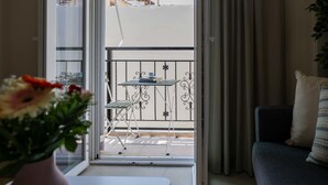 Un balcón con una mesa y sillas, una planta en maceta y vistas a edificios.