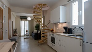 Una cocina moderna con armarios blancos, horno integrado y una escalera espiral que conduce a una sala de estar.