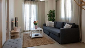Una sala de estar moderna con un sofá gris, una mesa de centro blanca y una mesita auxiliar con un jarrón de flores.