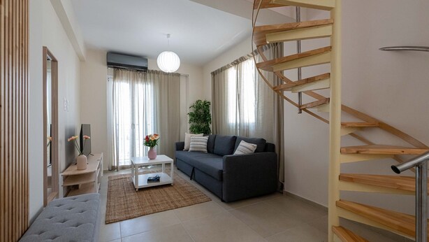 Una sala moderna con un sofá, una mesa de centro y una escalera de caracol.