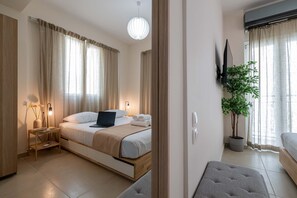 Una habitación de hotel moderna con cama, mesita de noche, lámpara, planta en maceta y televisor montado en la pared.