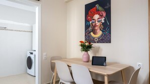 A dining area with a table, chairs, a vase with flowers, a tablet, and a washing machine in the background. - Home Easy Kalamata - Central Nest Private Parking (Kalamata)
