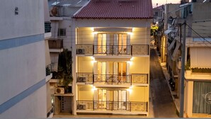 A multi-story building with balconies, a central entrance, and a small garden area. - Home Easy Kalamata - Central Nest Private Parking (Kalamata)