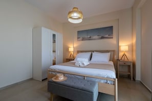 A neatly arranged bedroom with a bed, bedside lamps, a bench, and a wardrobe. - Home Easy Kalamata - Central Stylish Maisonette (Kalamata)