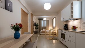 Een moderne keuken met witte kasten, een inbouwoven en een eethoek met een houten tafel en stoelen.
