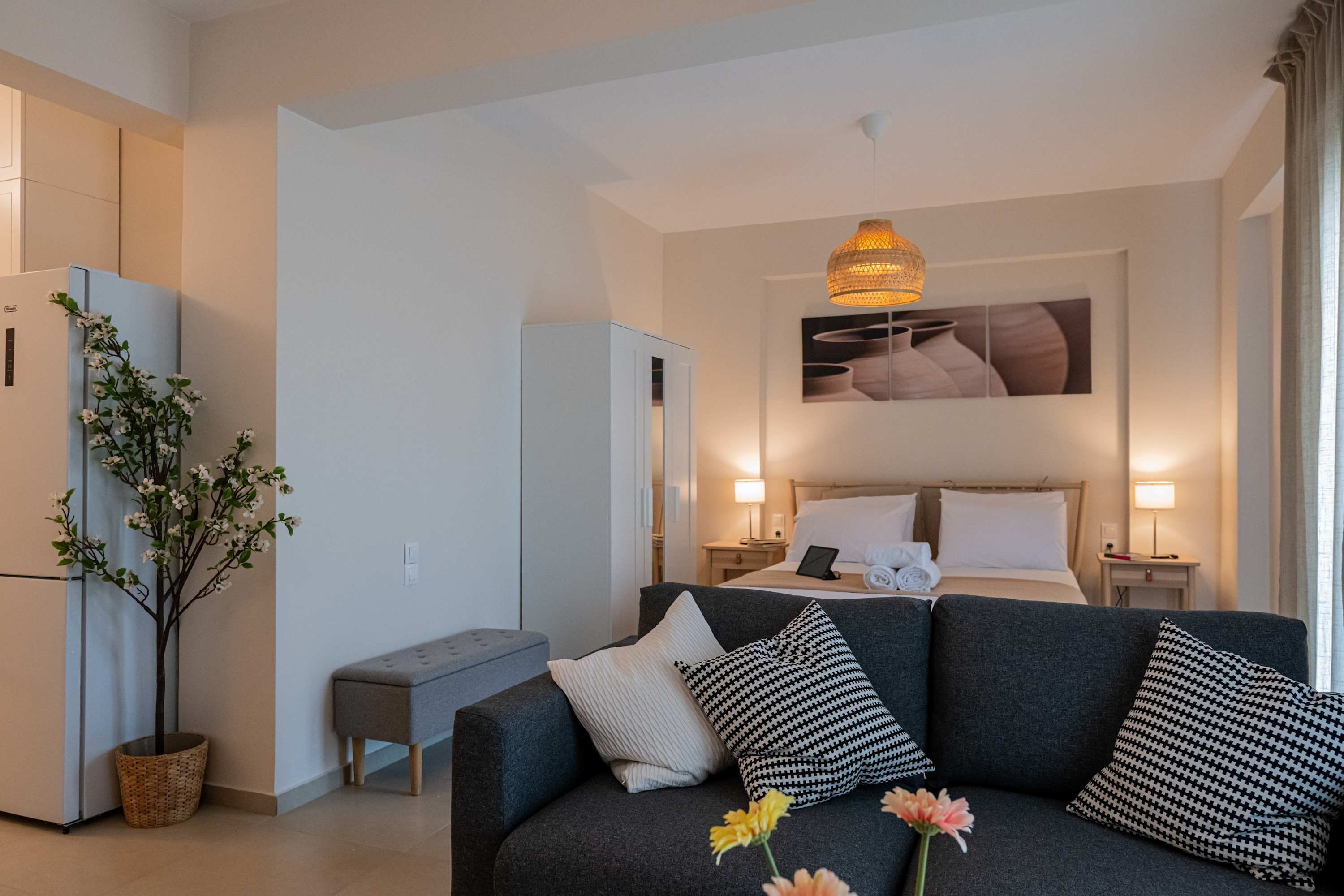 Une chambre d’hôtel moderne comprenant un lit, des tables de chevet, un canapé, un coin repas et une grande fenêtre.