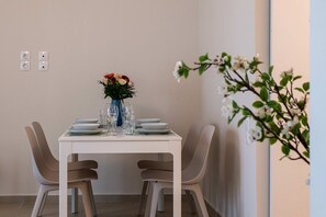 Una mesa de comedor con sillas, un jarrón con flores, y platos y vasos.