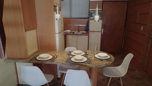 Een compacte keuken met een granieten aanrecht, vier witte stoelen en een eettafel voor vier personen gedekt.