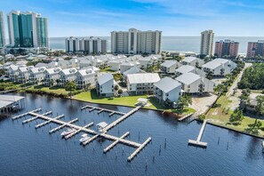 A marina with docked boats, a marina building, and residential buildings with a view of the ocean.