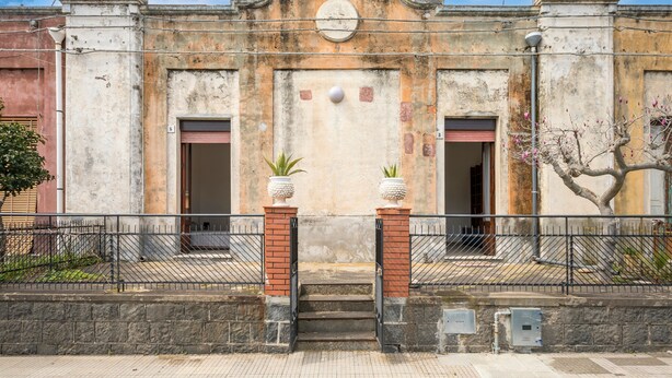 A building with a central entrance, two side doors, and a decorative archway. - La Papuzzella – Spacious Apartment with Terrace and Scenic Views (Mascali)