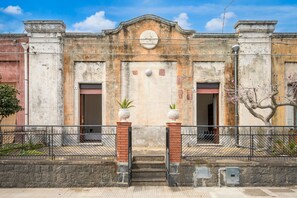 A building with a central entrance, two side doors, and a decorative archway. - La Papuzzella – Spacious Apartment with Terrace and Scenic Views (Mascali)