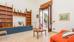 A living room with a sofa, a wooden coffee table, a blue cabinet, and a bookshelf. - La Papuzzella – Spacious Apartment with Terrace and Scenic Views (Mascali)