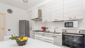 A modern kitchen with white cabinetry, a gas stove, a microwave, and an oven. - La Papuzzella – Spacious Apartment with Terrace and Scenic Views (Mascali)