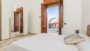 A bedroom with a bed, a mirror, and an open door leading to an outdoor area. - La Papuzzella – Spacious Apartment with Terrace and Scenic Views (Mascali)