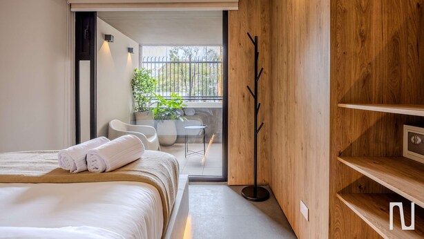 Ein modernes Hotelzimmer mit einem großen Bett, Holzboden, einem Balkon mit Blick und einem Kleiderhaken.