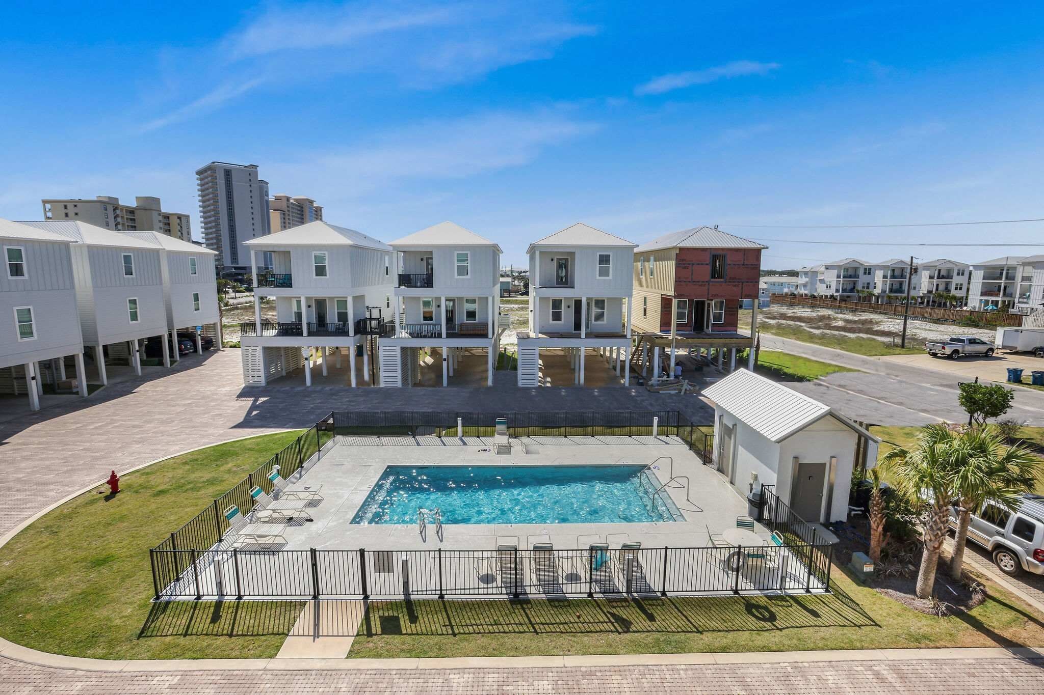 Área residencial com piscina, várias casas de dois andares e céu claro.