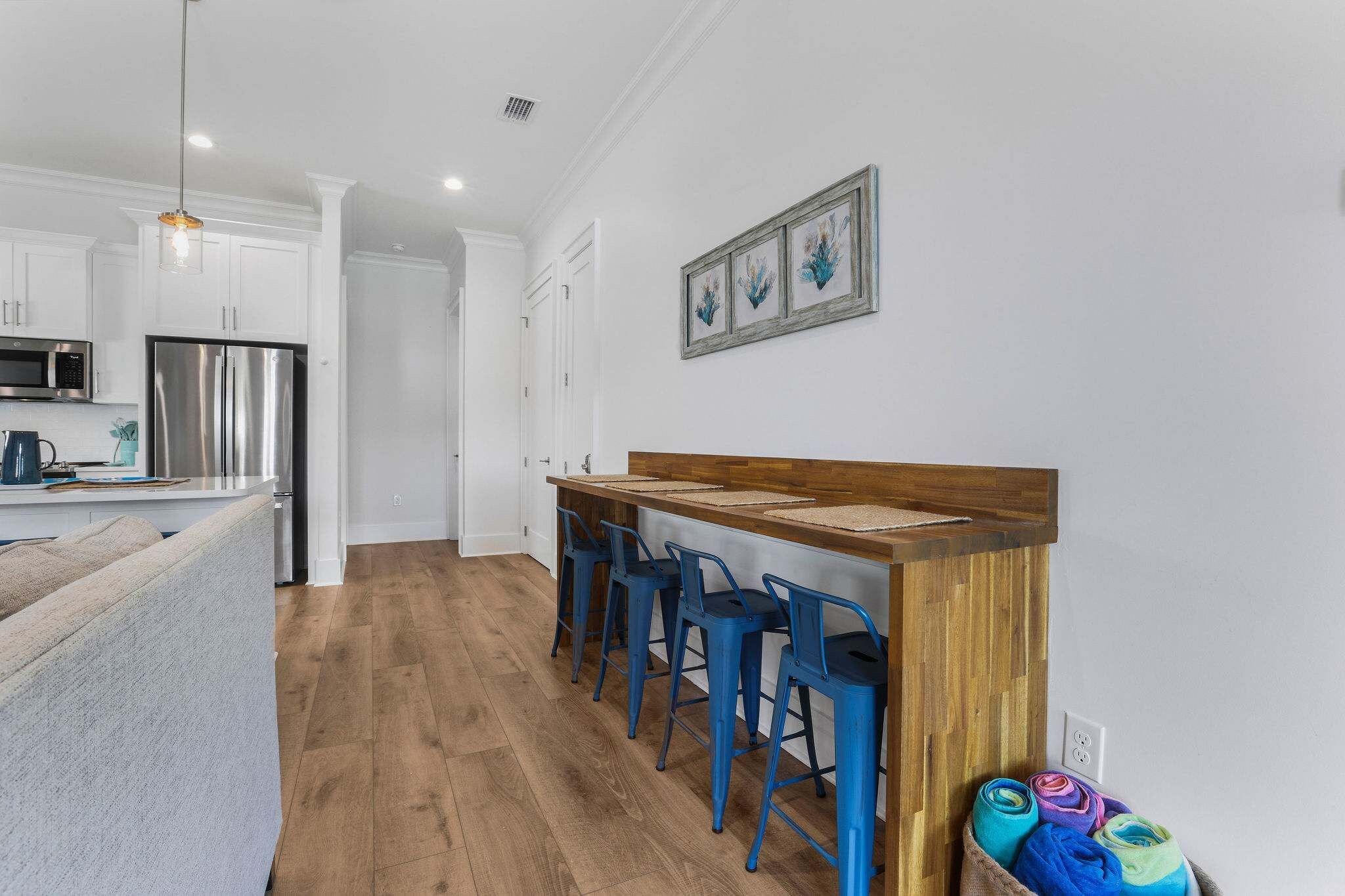 Eine moderne Küche mit einer Holzbar und blauen Barhocker, einem Edelstahlkühlschrank und einer Mikrowelle.