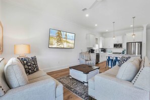 A modern living room with a sofa, coffee table, and a painting on the wall. - Whimsical Way- Beach Access  Pool  built in 2025 (Gulf Shores)