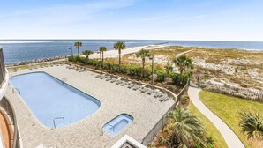 A rooftop pool with a view of the ocean, surrounded by palm trees and a sandy beach. - Grand Pointe 310  panoramic views  huge balcony  3rd floor with 3 bedrooms  3 5 baths (Orange Beach)
