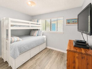 A room with a bunk bed, a television, and a window with blinds. - Las Palmas 114- Pool  BBQ  short walk to beach (Gulf Shores)