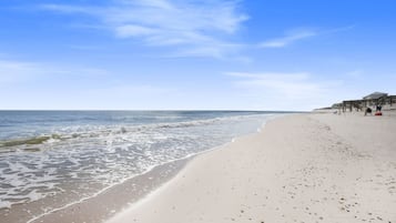 Une plage avec une jetée en bois et quelques personnes qui se promènent.