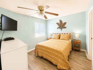 A bedroom with a bed, a ceiling fan, a television, and a window with blinds. - Las Palmas 114- Pool  BBQ  short walk to beach (Gulf Shores)