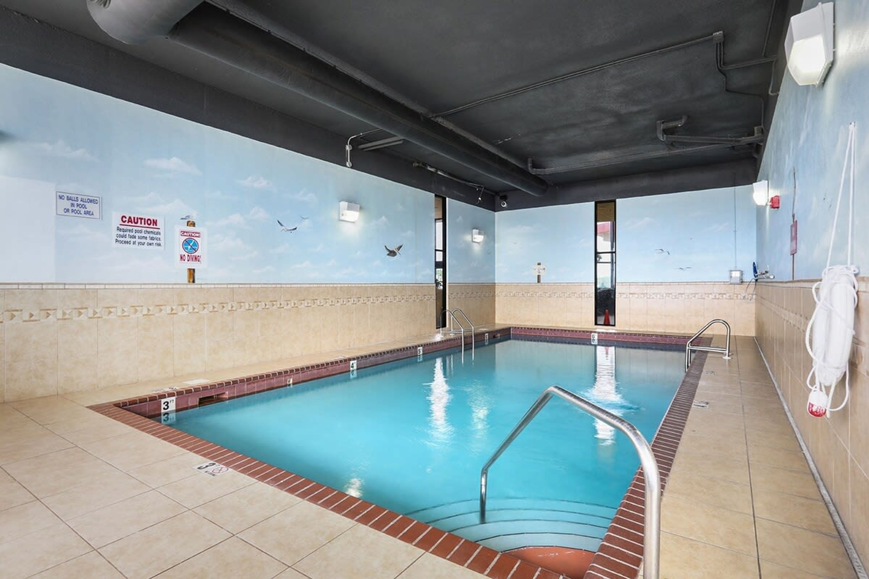 An indoor swimming pool with clear water, tiled walls, and a lifeguard chair.