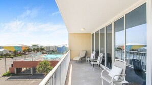 Un balcon avec vue sur la piscine, des chaises blanches et une table.