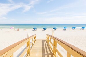 A wooden boardwalk leading to a beach with blue umbrellas and lounge chairs. - Lei Lani 218  Best of Beach   Bay (Orange Beach)